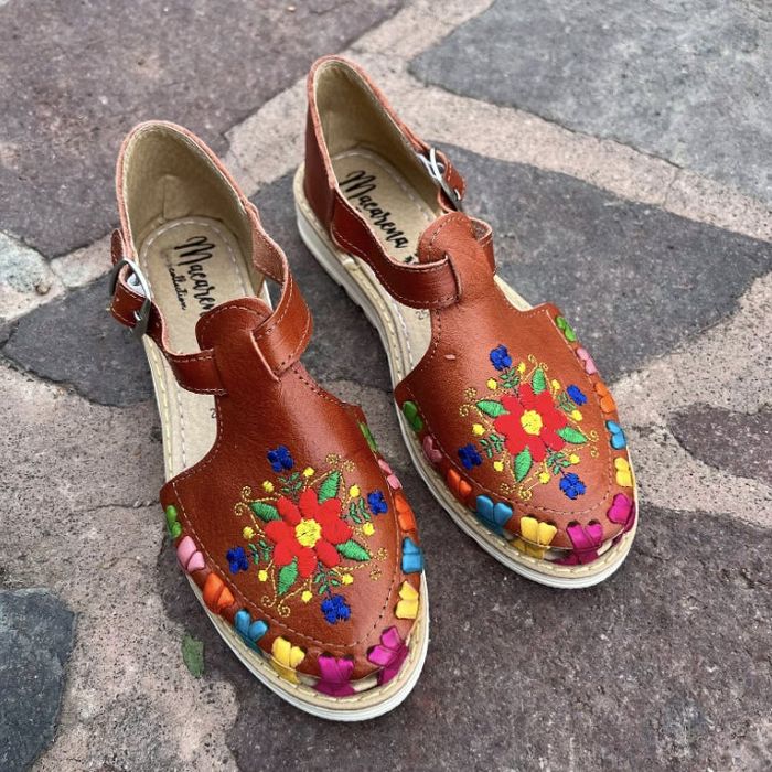 Leather sandals featuring floral embroidery with vibrant flowers and leaves adorning the toes and soles.