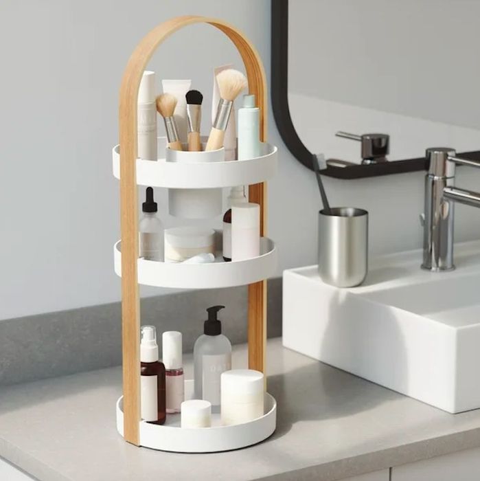 An organizer placed on a bathroom sink, filled with makeup and skincare products.