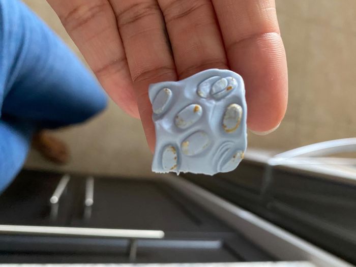 A blue putty square with earwax residue on it.