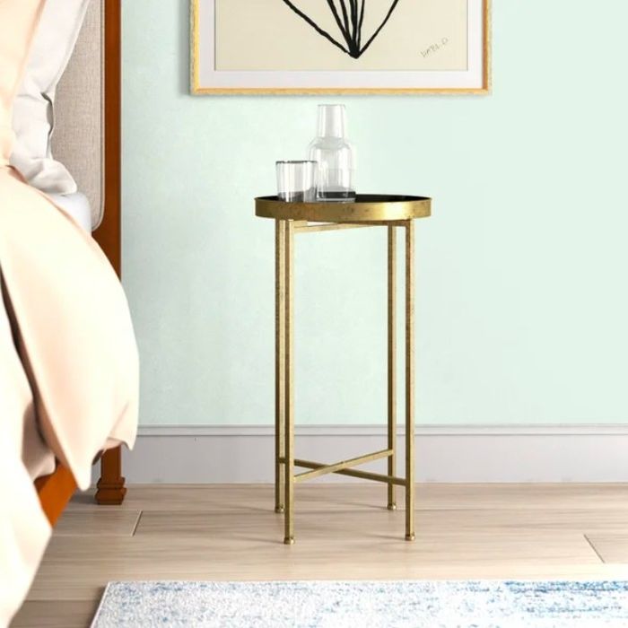 Gold end table placed beside a bed