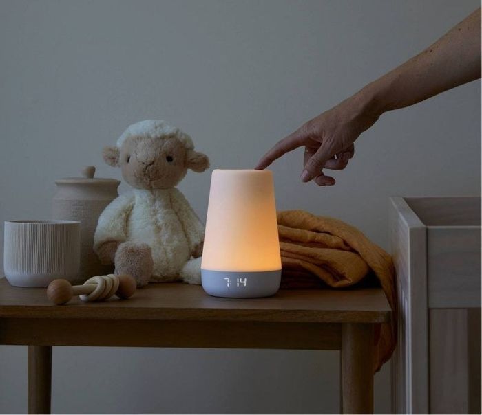 A hand touches the glowing sound machine, bringing it to life.