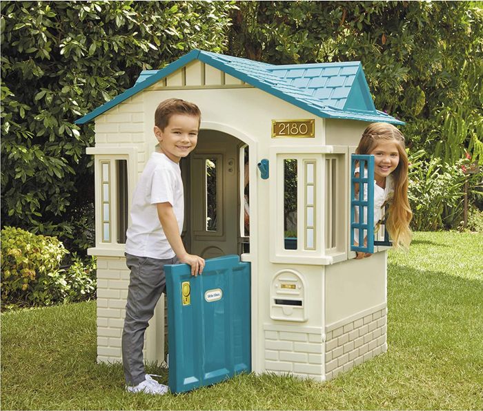 Two kids happily playing together inside a playhouse.