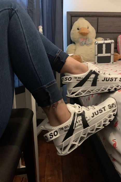 Reviewer showcasing white sneakers with black accents and a hollow, carved technology sole.