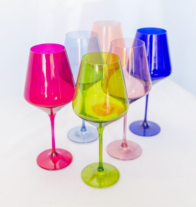 A collection of six colorful wine glasses, including shades of hot pink, lime green, light pink, lavender, blue, and light blue.