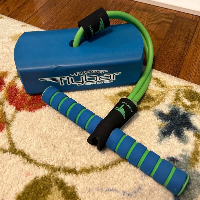 Flybar foam pogo jumper with green and blue handles, designed for both indoor and outdoor fun, placed on a colorful patterned rug.