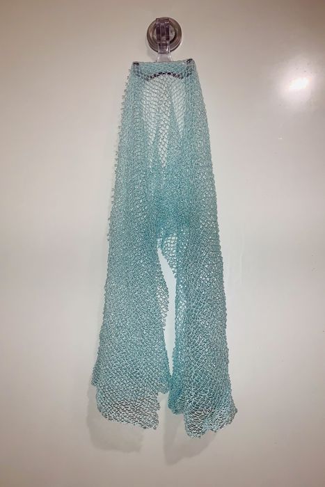 A photo of a Luv Scrub hanging in a shower, ready for use.