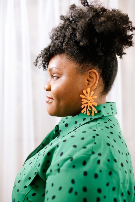 A model showcasing the earrings in orange