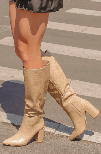 A model showcasing the knee-high boots in light nude croc.