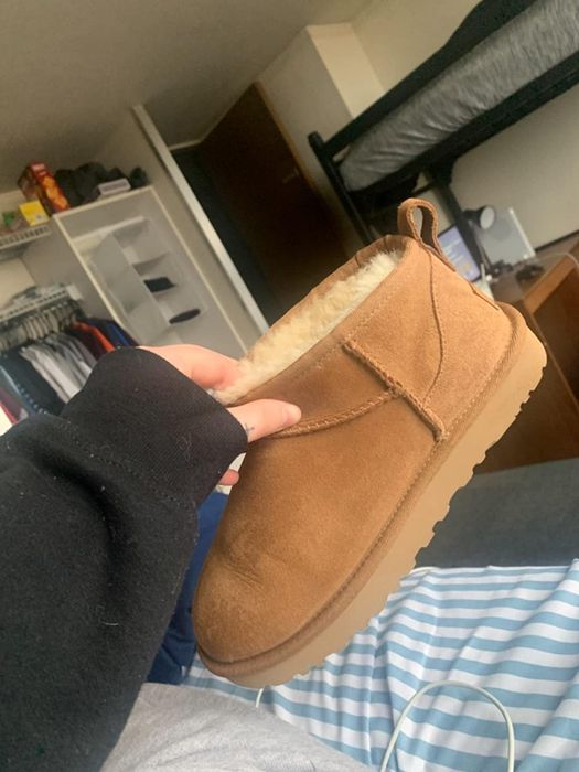A reviewer holding a pair of short brown Ugg boots.