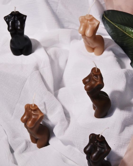 A collection of torso-shaped candles in various skin tones.