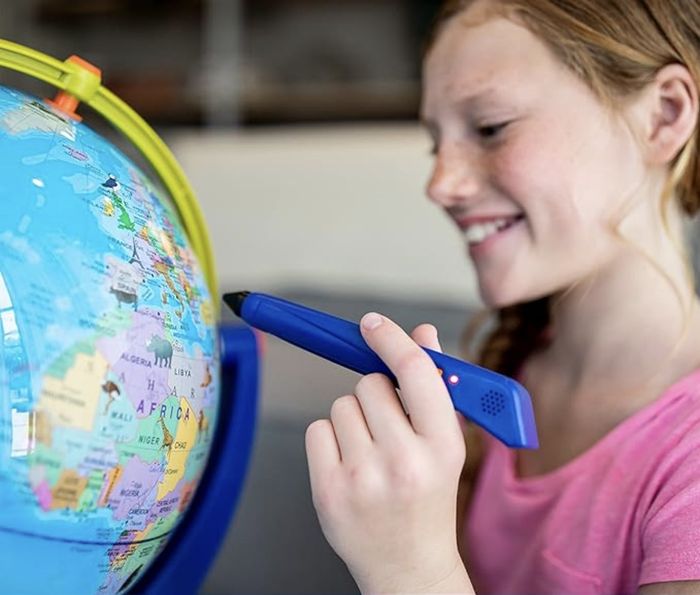 A young child with braided hair using an interactive pen on a globe for an educational activity
