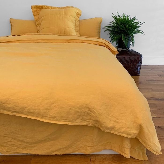 A bed adorned with vibrant yellow linen sheets.