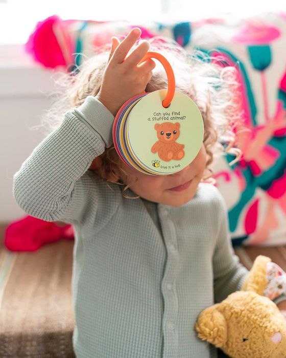 A child holding the ring of scavenger hunt cards up to their face, ready to play.