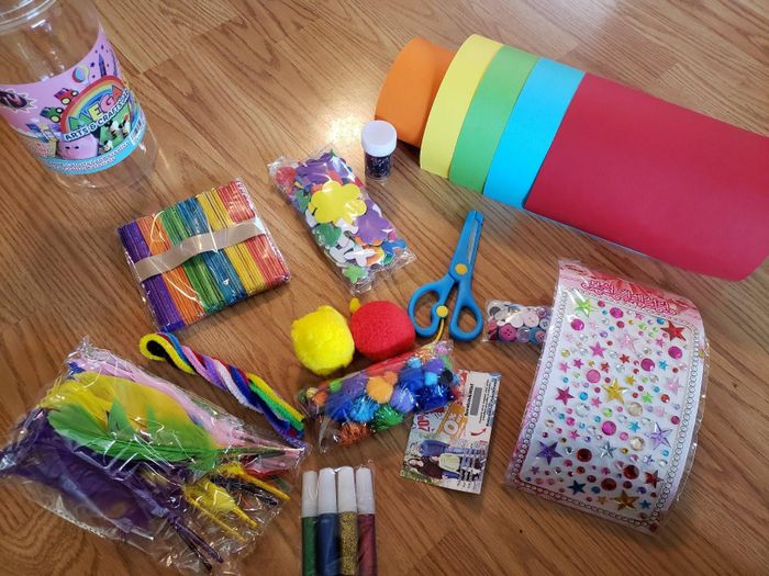 The reviewer displaying the contents of the craft supplies kit, featuring scissors, paper, stickers, and much more
