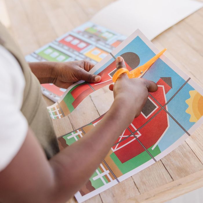 Another child carefully cutting the paper using scissors.