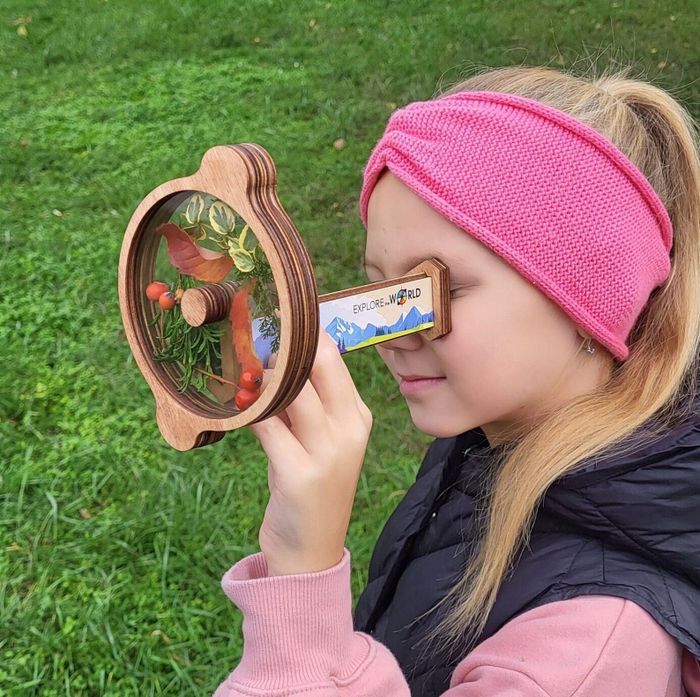 A child gazing through the wooden kaleidoscope filled with colorful flowers.