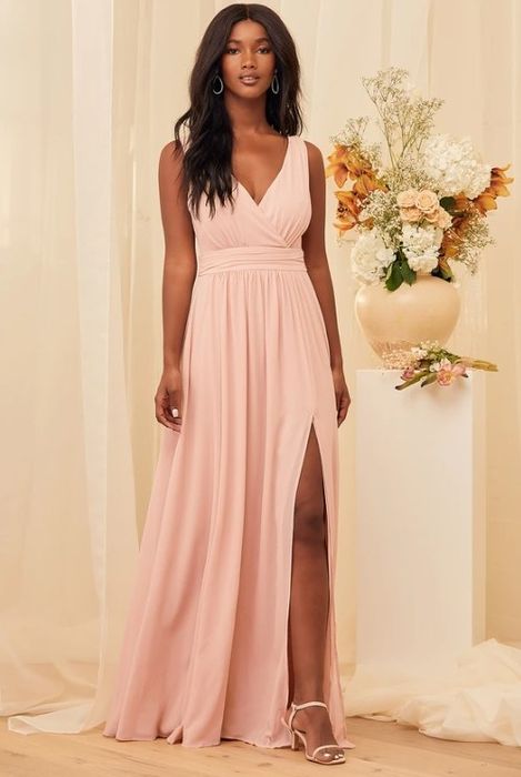 An image of a model wearing a blush surplice maxi dress with a sleeveless design, V-back, and a chic side slit