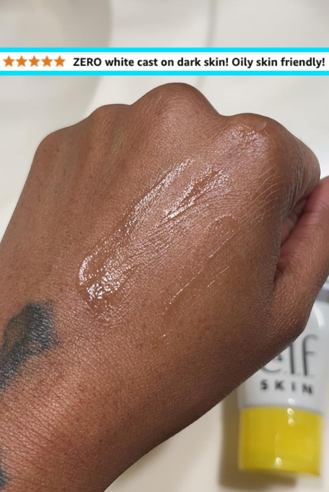 A reviewer showing the sunscreen applied to dark skin, with no white residue visible.