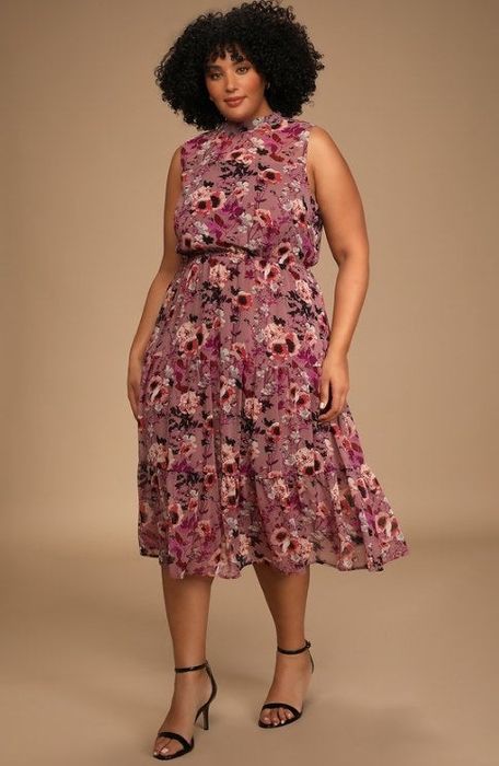 An image of a model wearing a floral midi dress with a mock neck, a keyhole back, and button detailing.