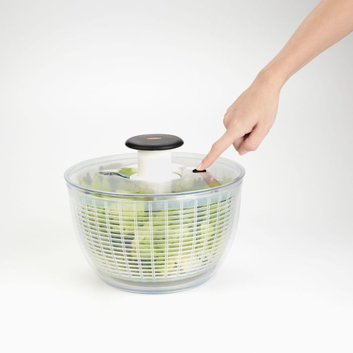 A person using a salad spinner to clean fresh greens.