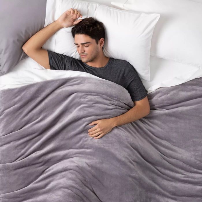 A model wrapped in a cozy grey weighted blanket