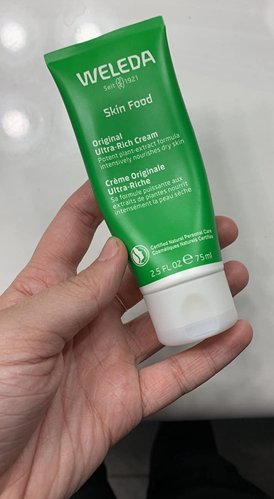 Reviewer holding a jar of Weleda Skin Food