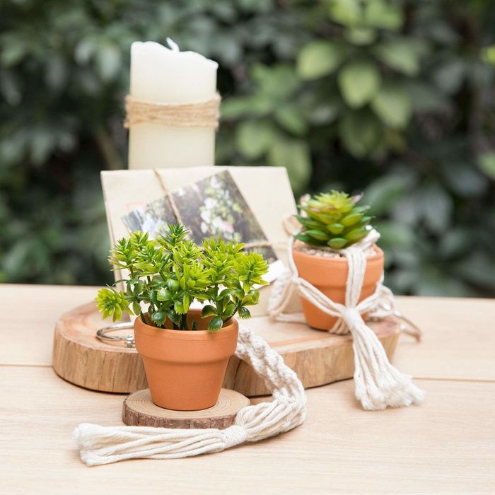 Two artificial plants placed inside terra cotta planters, hanging from macrame holders.