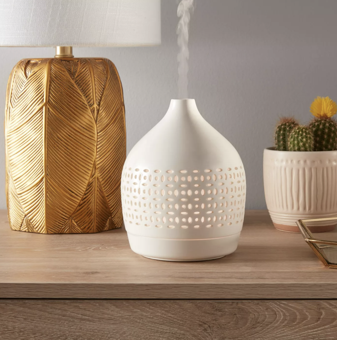 A white oil diffuser elegantly placed on a countertop, designed to enhance the ambiance of any room with a calming, aromatic presence.
