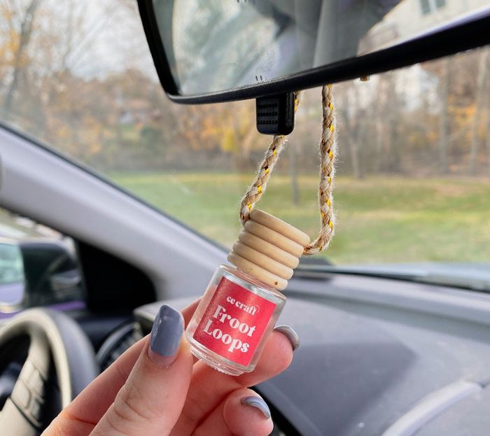An air freshener in a small jar, labeled “Froot Loops,” hanging from a car mirror.