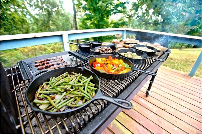Cast-iron skillets being used to prepare meals outdoors.