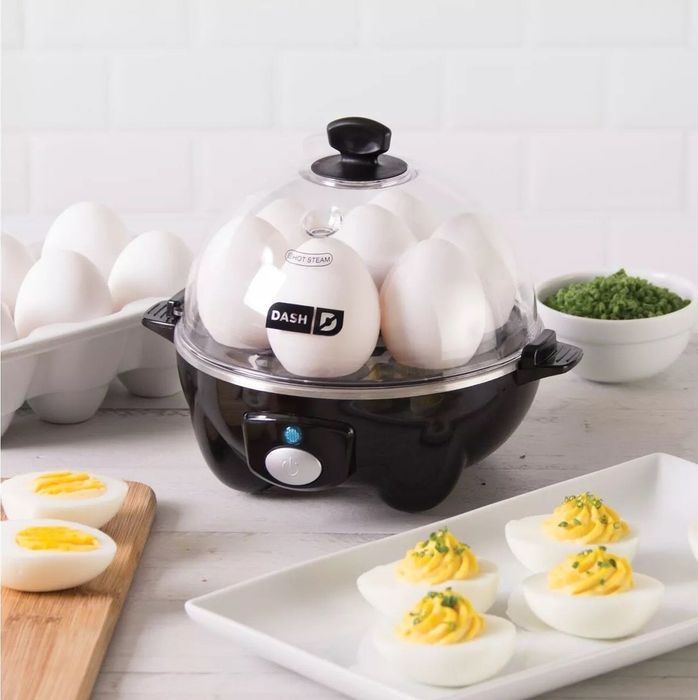 A black egg cooker with a plate of deviled eggs displayed beside it.