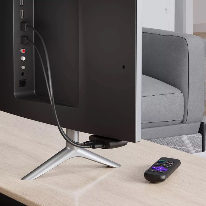 A black remote and an HDMI cable plugged into the back of a TV.