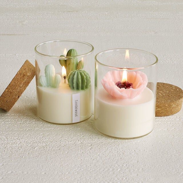 A white candle adorned with intricately crafted wax peony and cactus details.