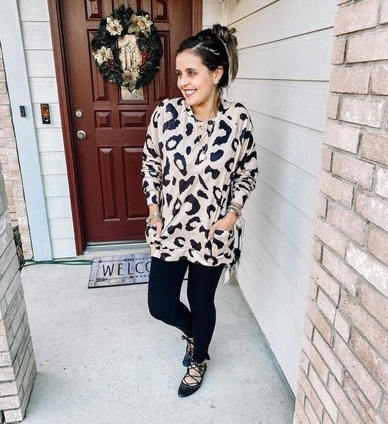 The reviewer is wearing the sweatshirt, featuring two side pockets, in a trendy leopard print.