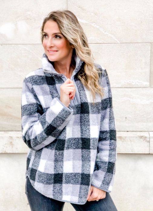 The reviewer is seen wearing the fuzzy quarter zip in a chic black, grey, and white plaid pattern.