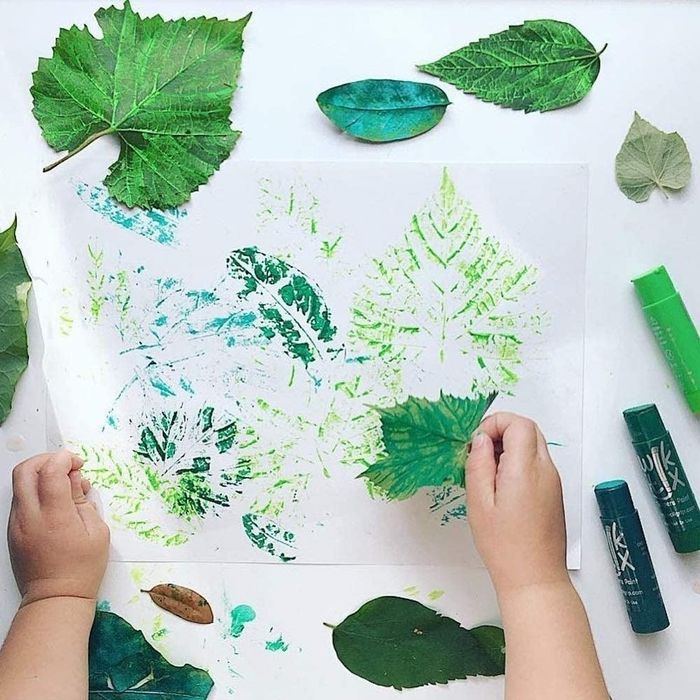A young child using paint sticks to create colorful artwork.