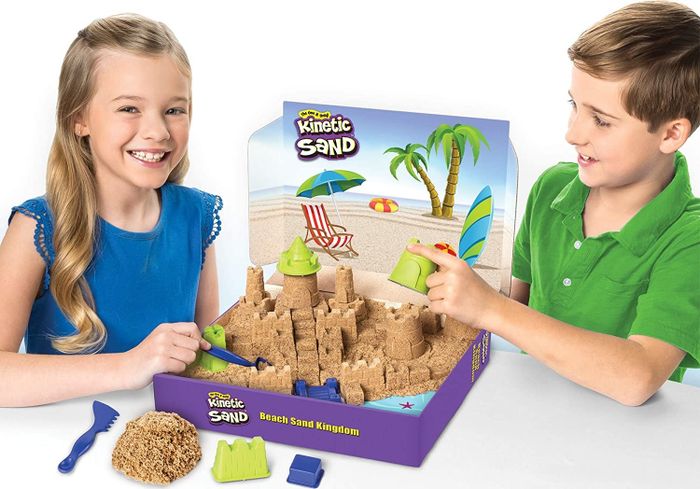 Two children build a sandcastle using Kinetic Sand, enjoying tactile fun together.