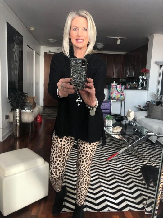 A reviewer showing off the leggings in a tan and black leopard print design.
