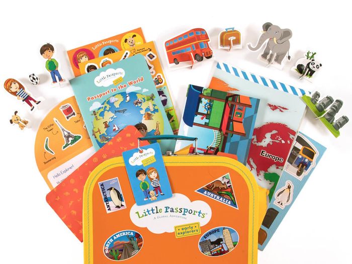 A subscription kit that includes a world map, cardboard figures, and a toy suitcase