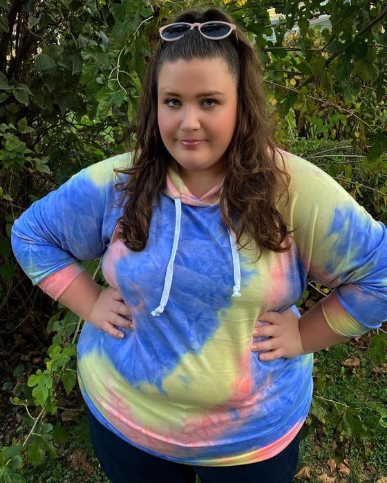 A different reviewer sports the tie-dye sweatshirt in a vibrant mix of blue, yellow, and pink.