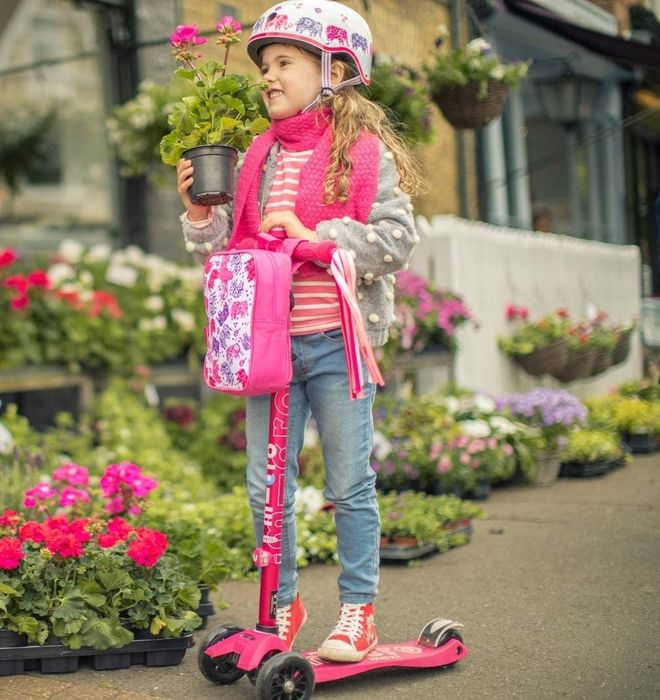 A child riding a pink scooter