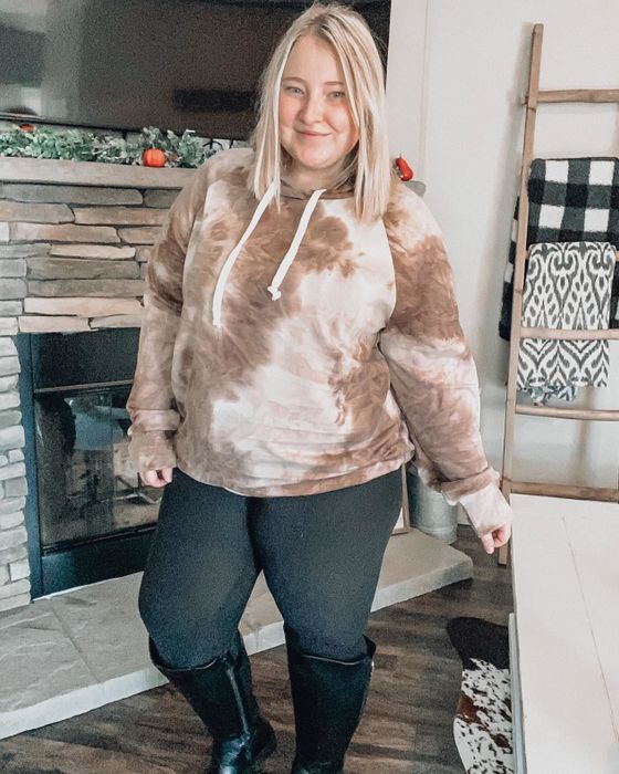 A reviewer models the tie-dye sweatshirt in a rich brown color.