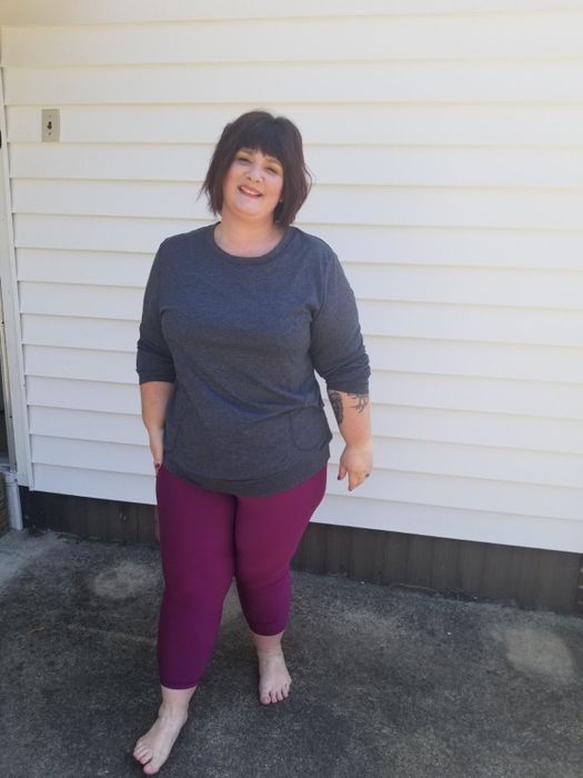 A reviewer is seen wearing the tee in a stylish dark grey shade.