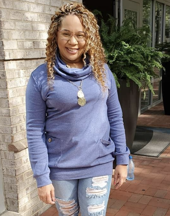 The reviewer is dressed in a chic cowl neck sweater in a rich blue hue.