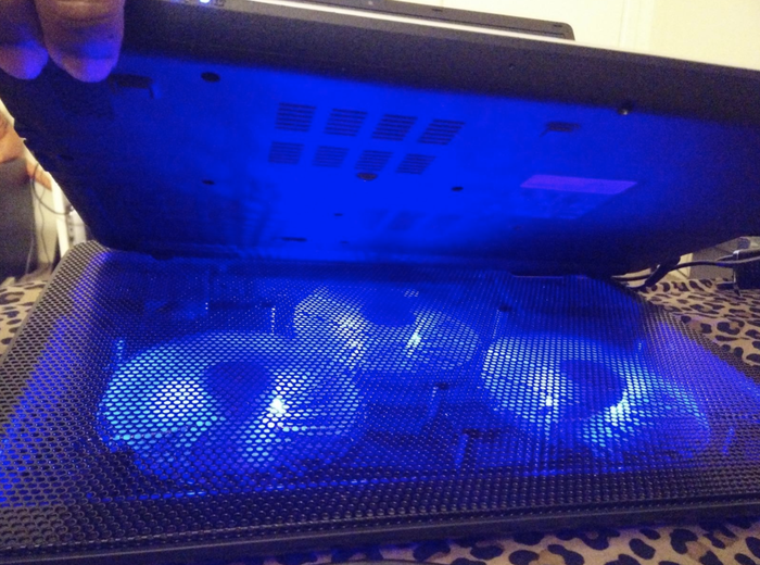 A reviewer captures a photo of the cooling pad emitting a soft blue light.