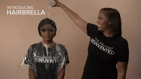 A model pouring water over another model's head while they're wearing the Hairbrella, then removing it to reveal perfectly styled, dry hair.