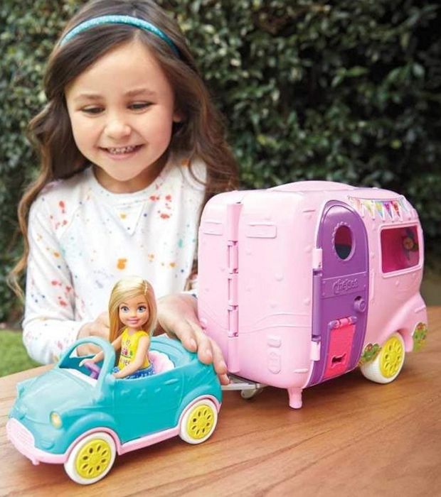 A child having fun with a Barbie doll camper set.