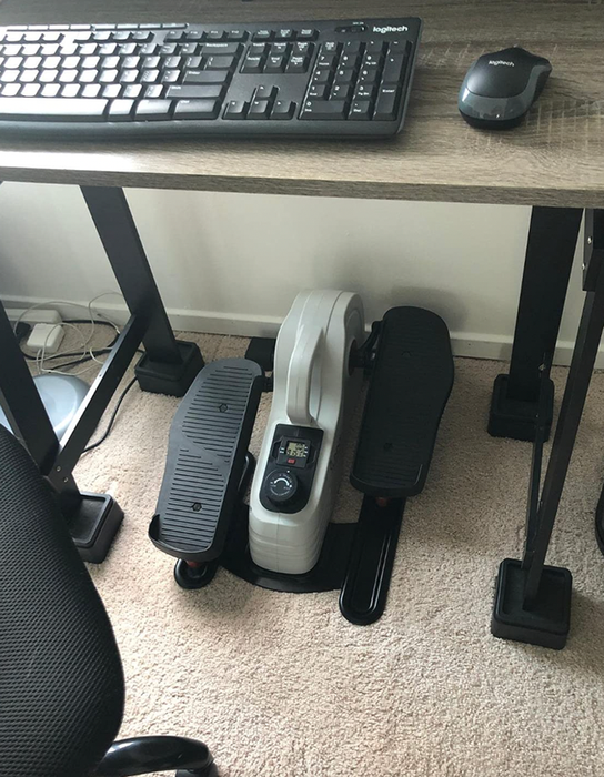 A compact black and silver elliptical machine designed for use under a desk.