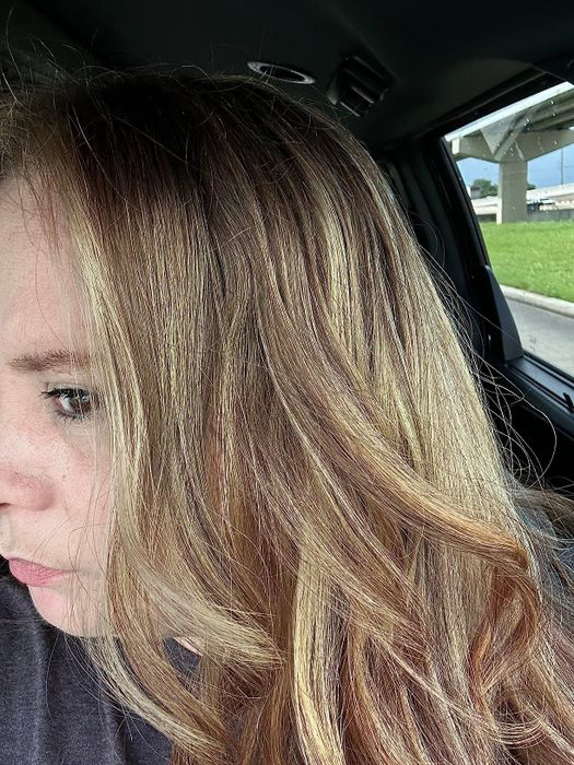 Close-up of a person with long, wavy hair sitting inside a car