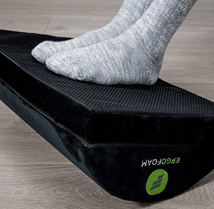The footrest flipped over to its flat side, with a model resting their feet comfortably.